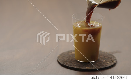 pour espresso in glass with orange juice to make Bumble coffee pour espresso in glass with orange juice to make Bumble coffee 141907661