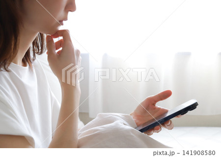 スマホを見て悩む女性 スマホを見て悩む女性 141908580