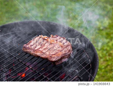 Juicy Beef Steak Grilling on Charcoal Barbecue in Garden Juicy Beef Steak Grilling on Charcoal Barbecue in Garden 141908643