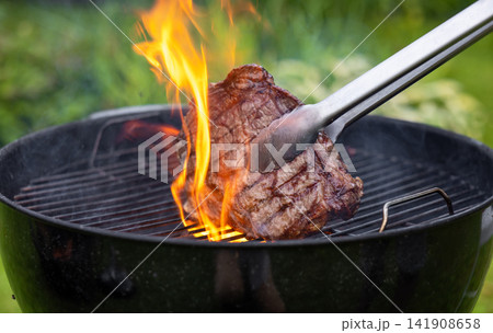 Juicy Beef Steak Grilling on Charcoal Barbecue in Garden Juicy Beef Steak Grilling on Charcoal Barbecue in Garden 141908658