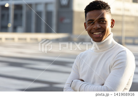 African American teen standing on plaza in white turtleneck, paving or railing or building, copy spa 141908916