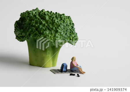 Miniature woman resting under green broccoli Miniature woman resting under green broccoli 141909374