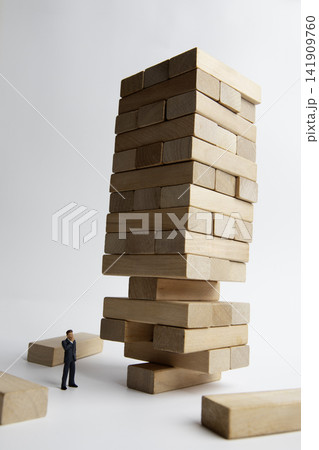 Precarious wooden blocks and miniature businessman 141909760