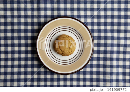 A oatmeal cookie on a blue and white checkered tablecloth 141909772