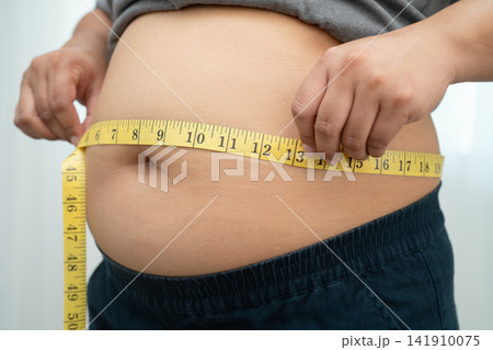 Asian woman with fat belly big size overweight and obesity with measure tape. 141910075