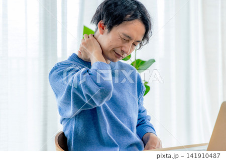 自宅でテレワーク中に首の痛みを感じる若い男性 自宅でテレワーク中に首の痛みを感じる若い男性 141910487