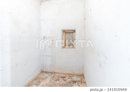 Empty dilapidated room with grimy white walls and small window Empty dilapidated room with grimy white walls and small window 141910949