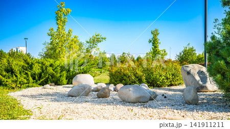 Large smooth boulders and white gravel stones decorative landscaping in summer city park, zen garden design concept 141911211