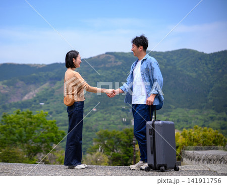 旅行先で握手をする若い男女のカップル 141911756