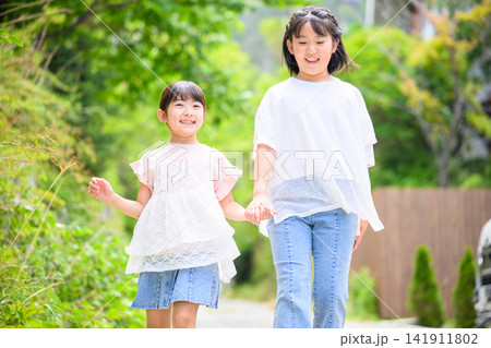 手をつないで楽しそうに歩く二人の女の子 手をつないで楽しそうに歩く二人の女の子 141911802