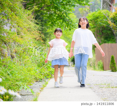 手をつないで笑顔で歩く姉妹 141911806