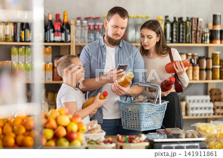 Young family with little son scanning QR on bottle of juice in supermarket Young family with little son scanning QR on bottle of juice in supermarket 141911861