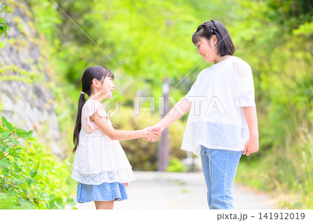自然の中で仲良く手をつなぐ二人の女の子 自然の中で仲良く手をつなぐ二人の女の子 141912019