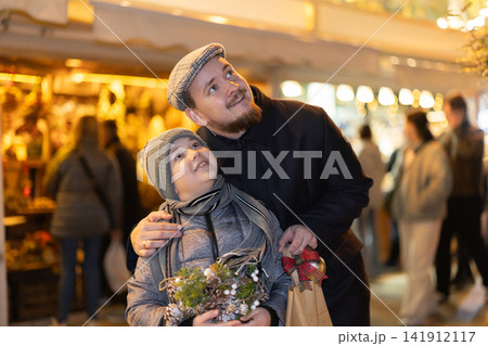 Man with son stands in middle of shopping area decorated for New Year holidays Man with son stands in middle of shopping area decorated for New Year holidays 141912117