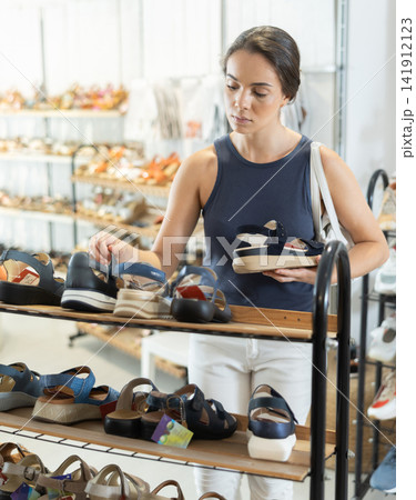 Young woman choosing sandals in shoe store Young woman choosing sandals in shoe store 141912123