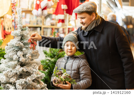 Dad and son are standing near the Christmas tree 141912160