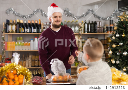 Man seller weighs tangerines for boy buyer 141912228