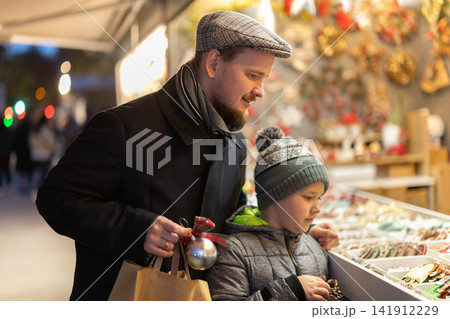Man with son in outdoor souvenir shop examines Christmas toys Man with son in outdoor souvenir shop examines Christmas toys 141912229