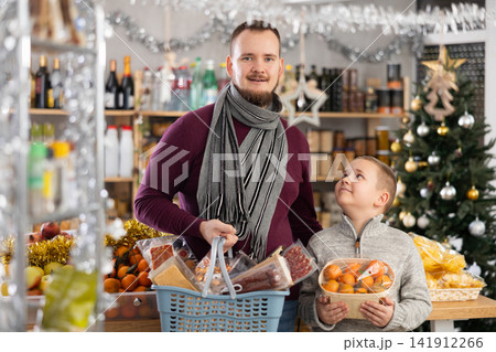 Father and son standing in festive market with chosen products in hands 141912266