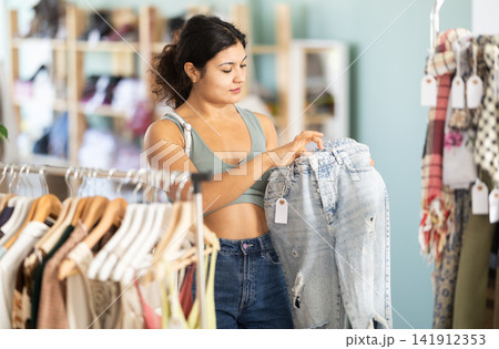 Young woman choosing jeans in clothing store Young woman choosing jeans in clothing store 141912353