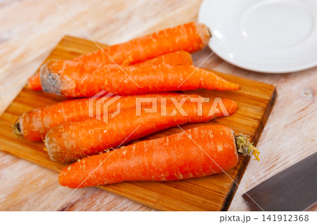 Bunch of fresh carrots on wooden cutting board Bunch of fresh carrots on wooden cutting board 141912368