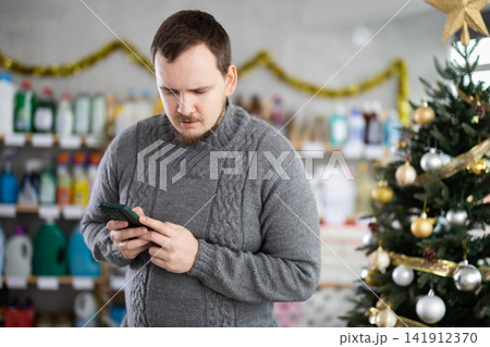 Male buyer in household chemicals store types message Male buyer in household chemicals store types message 141912370