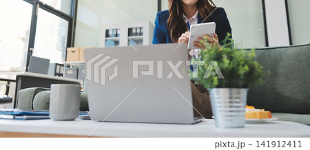 Asian businesswoman sitting at work using laptop talking and consulting in office 141912411