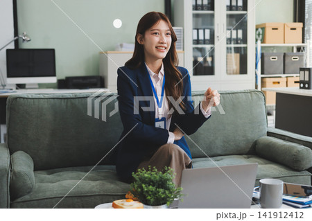 Asian businesswoman sitting at work using laptop talking and consulting in office Asian businesswoman sitting at work using laptop talking and consulting in office 141912412