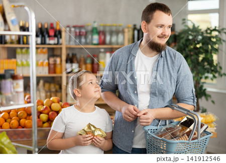 Young man shopping together with preteen son in grocery store Young man shopping together with preteen son in grocery store 141912546
