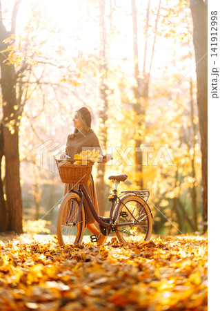 Stylish woman with a bicycle enjoying autumn weather in the park. Beautiful Woman in the autumn forest. Stylish woman with a bicycle enjoying autumn weather in the park. Beautiful Woman in the autumn forest. 141912998
