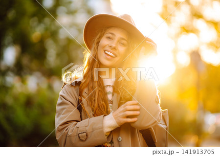 Portrait of a stylish smiling woman walking in park. street style in hat. Concept of nature, relax. Portrait of a stylish smiling woman walking in park. street style in hat. Concept of nature, relax. 141913705