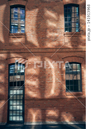 historic brick building facade with industrial loft windows and sunlight shadows, renovated urban brick architecture exterior with symmetrical windows and modern design details historic brick building facade with industrial loft windows and sunlight shadows, renovated urban brick architecture exterior with symmetrical windows and modern design details 141913968