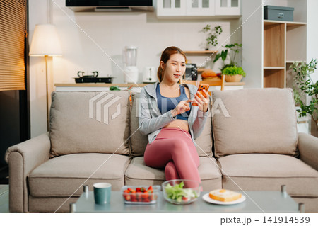 Young woman enjoying healthy meal at home after workout, clean eating lifestyle concept, fitness diet, wellness routine in cozy modern living space. 141914539