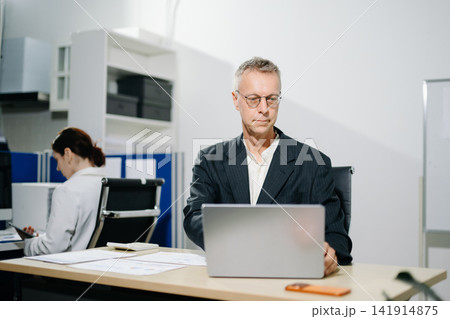 businessman and young corporate woman discussing strategic reports at office desk. Professional collaboration and workplace mentoring. businessman and young corporate woman discussing strategic reports at office desk. Professional collaboration and workplace mentoring. 141914875