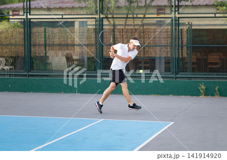 Male tennis player hitting ball on court Male tennis player hitting ball on court 141914920