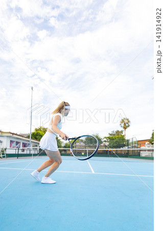 Woman athlete playing tennis on blue court Woman athlete playing tennis on blue court 141914922