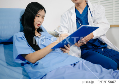 Patient reviewing and signing medical consent documents with healthcare staff during hospital registration, consultation, treatment preparation and care. 141915067