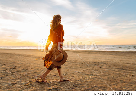 Beautiful woman at windy spring day relaxing on coast. Lady looking at sunset. Travelling, lifestyle Beautiful woman at windy spring day relaxing on coast. Lady looking at sunset. Travelling, lifestyle 141915285