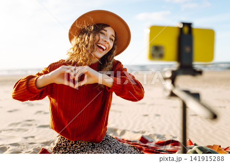 Style woman using smartphone with stabilizer, taking pictures in on sea beach. Woman creates content Style woman using smartphone with stabilizer, taking pictures in on sea beach. Woman creates content 141915288