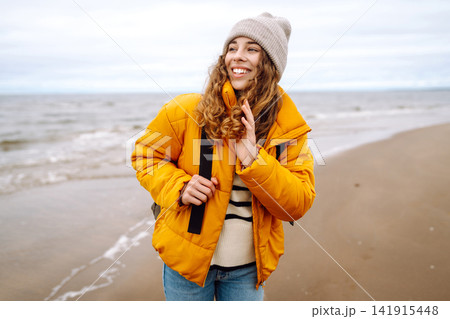 Attractive woman on a windy cold beach. Travel, nature concept. 141915448