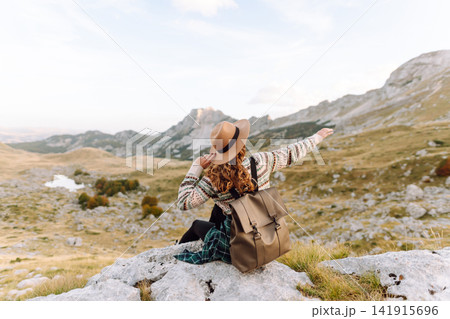 Happy woman stands on rocky terrain, gazing out at breathtaking landscape before her. Lifestyle. 141915696