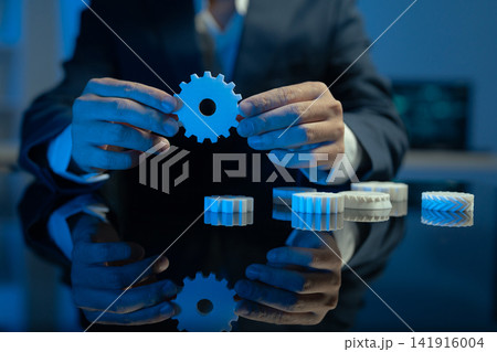 Asian businessman holding a gear cog against a computer screen, technology, engineering, automation, system optimization, efficiency, and digital innovation. Asian businessman holding a gear cog against a computer screen, technology, engineering, automation, system optimization, efficiency, and digital innovation. 141916004