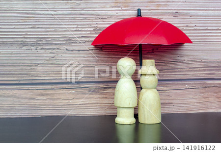 Minimalist elderly figures sheltered under a red umbrella representing safety, leadership and financial security 141916122