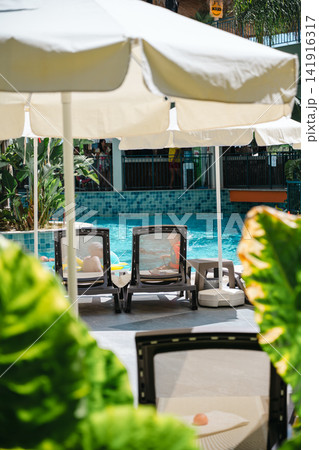 Resort swimming pool with sun umbrellas and lounge chairs Resort swimming pool with sun umbrellas and lounge chairs 141916317