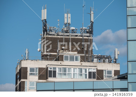 Corby, Northamptonshire, UK - August 2, 2026: Telecommunications antennas on rooftop of office building in Corby, England Corby, Northamptonshire, UK - August 2, 2026: Telecommunications antennas on rooftop of office building in Corby, England 141916359