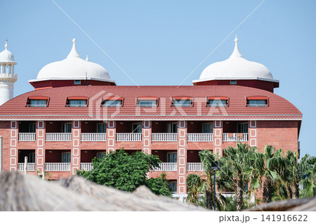 Red resort hotel with domed architecture and palm trees, travel holiday leisure background Red resort hotel with domed architecture and palm trees, travel holiday leisure background 141916622