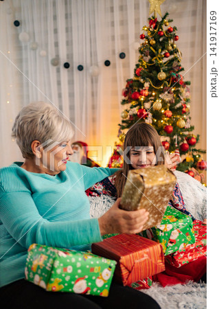 Grandmother and granddaughter celebrating Christmas opening gifts at home Grandmother and granddaughter celebrating Christmas opening gifts at home 141917169
