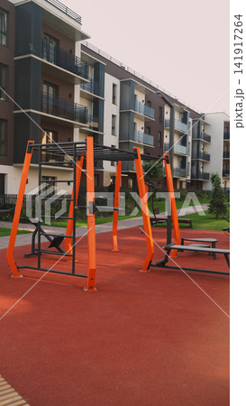 Outdoor gym equipment with monkey bars on a rubber surface in front of a modern apartment building complex Outdoor gym equipment with monkey bars on a rubber surface in front of a modern apartment building complex 141917264