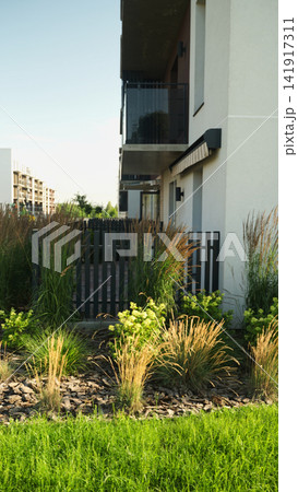 Modern apartment building exterior with green landscaping and decorative grasses on a summer day Modern apartment building exterior with green landscaping and decorative grasses on a summer day 141917311