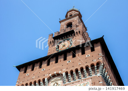 Filarete Tower Clock of Sforza Castle Brick Facade against Blue Sky in Milan City Center Italy Filarete Tower Clock of Sforza Castle Brick Facade against Blue Sky in Milan City Center Italy 141917469